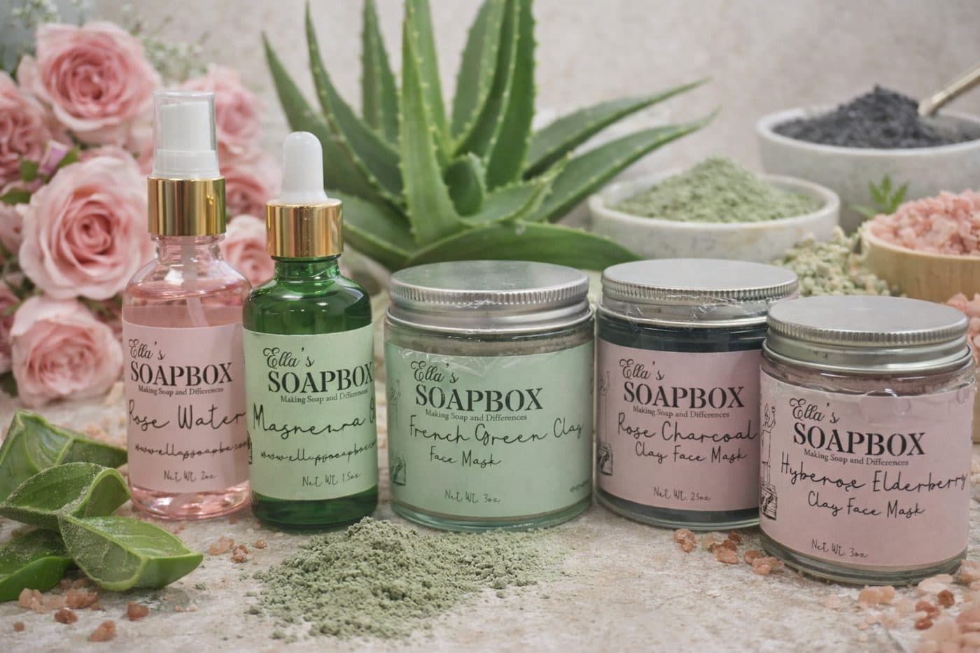 Clay face mask jars and facial waters among roses and aloe
