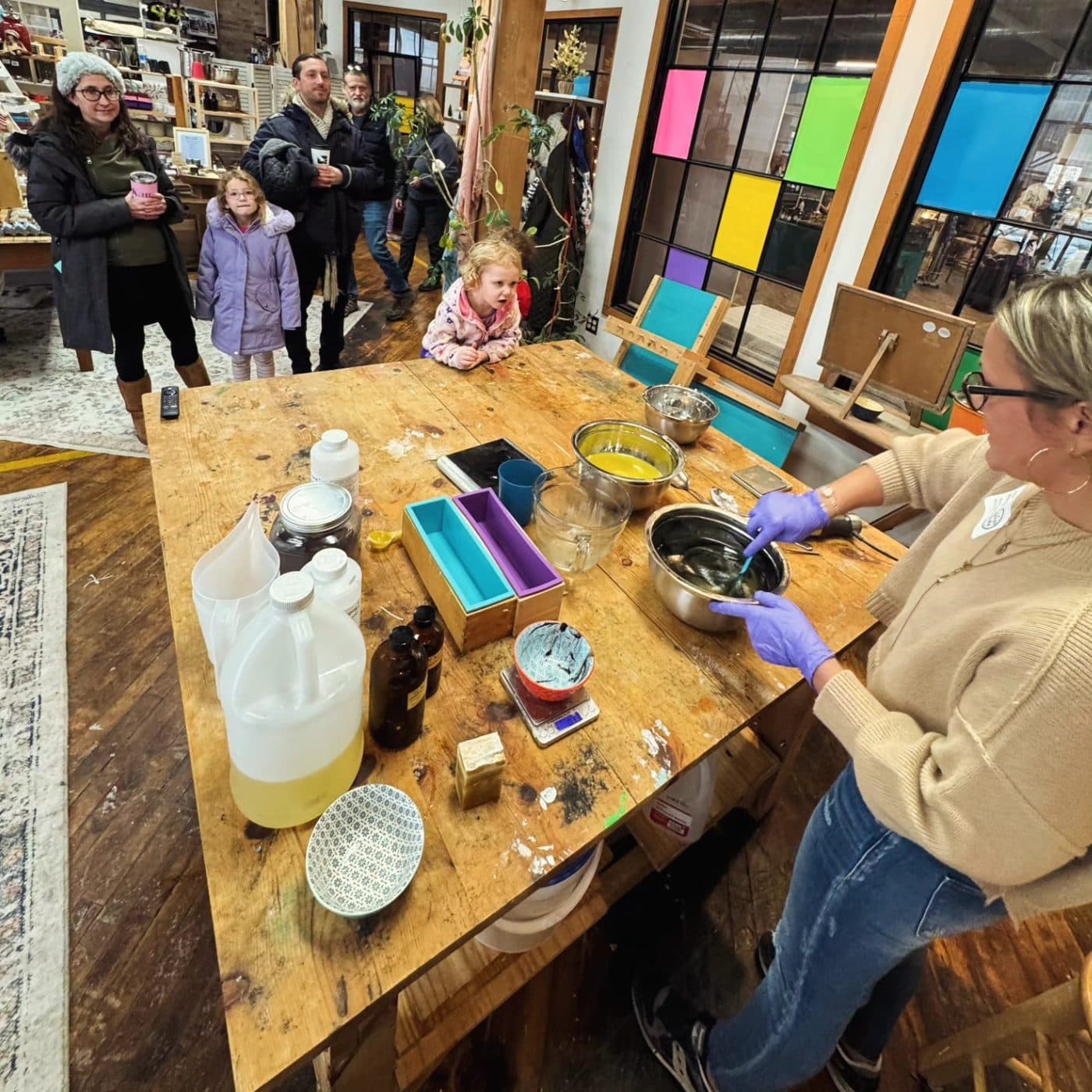Soapmaking at a long wooden table while visitors watch